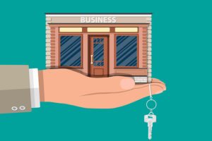 hand holding a miniature business establishment and a key