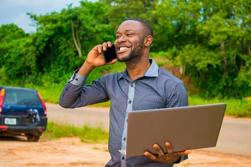 Young businessman on a call while holding his laptop with one hand.