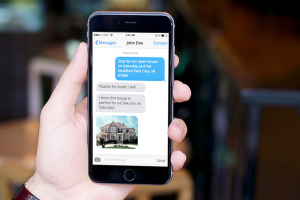 Man's hand holding a phone with real estate text message on it