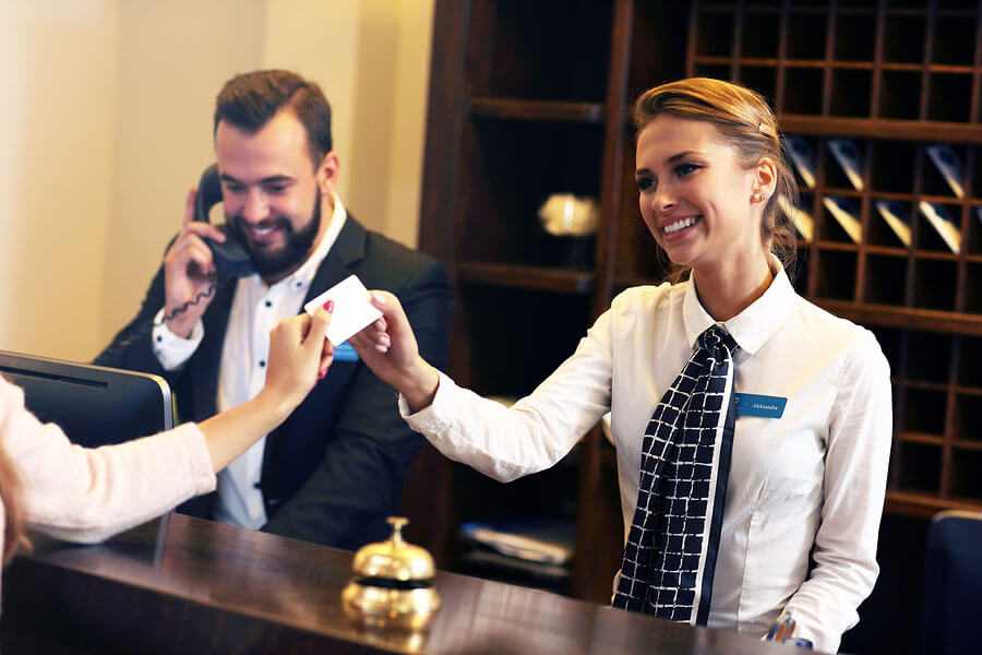 Hotel receptionist accepting card from a customer.