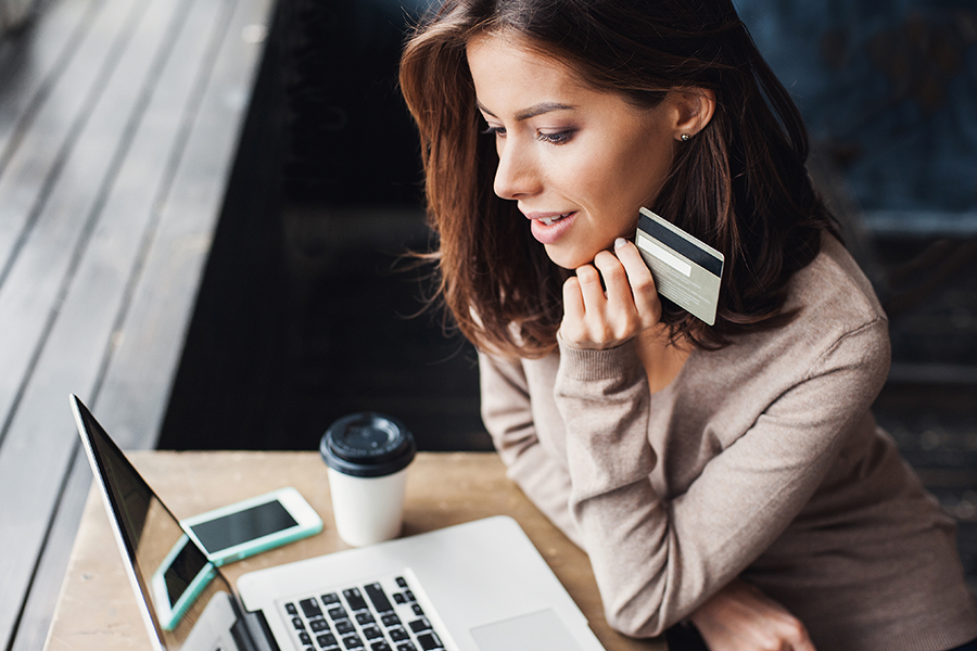 businesswoman holding credit card while looking at laptop