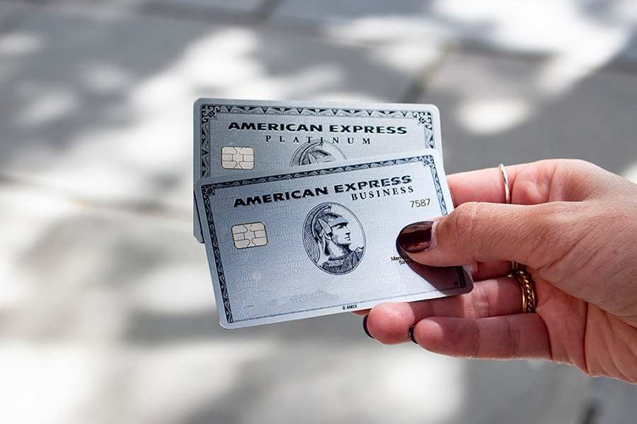 A hand holding Two American Express Business Card.