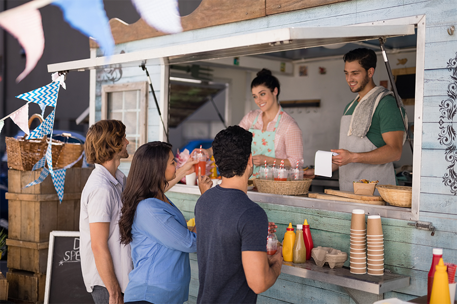 man and woman in food truck getting orders from customers