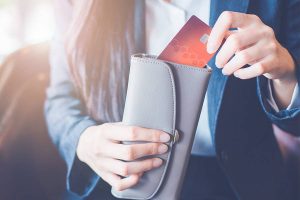 Woman holding a wallet and a red credit card.