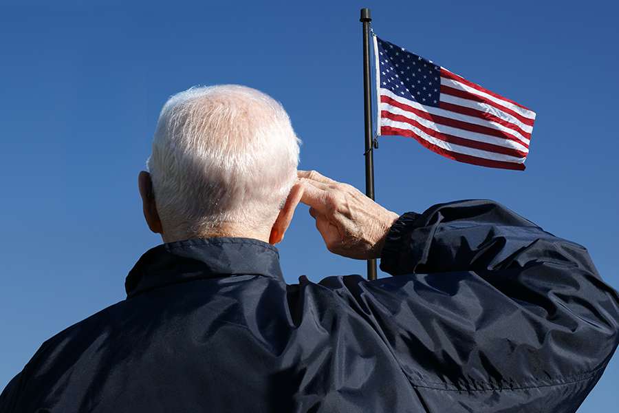 veterans saluting infront of USA flag