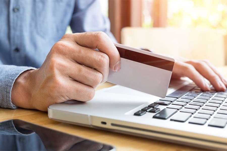Man holding credit card while browsing on laptop.