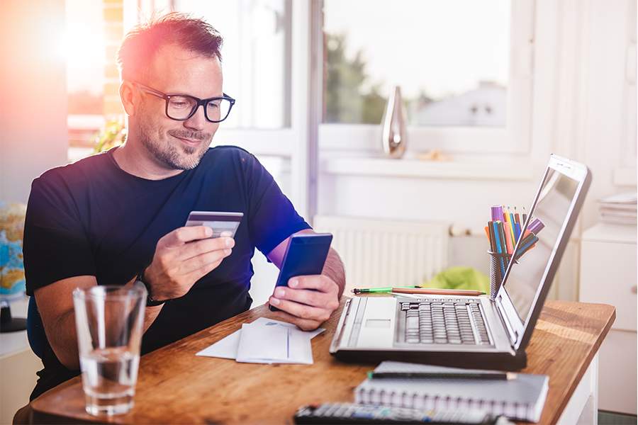 Young man looking his own credit card and mobile phone.