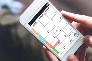 Holding a phone with calendar app on it.