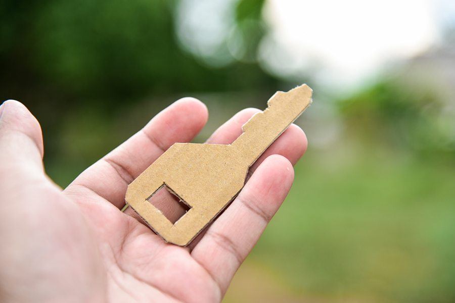 Hand holding a key made with cardboard.