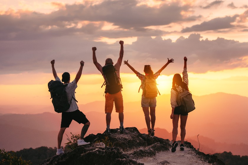 Hikers on mountain top facing the sunset.