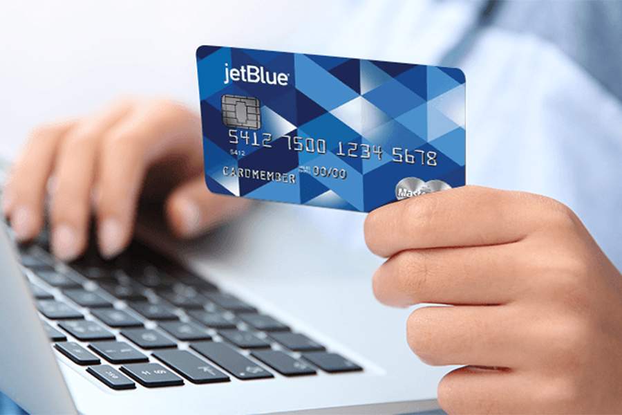 Man's hand holding a JetBlue credit card for shopping payment online.