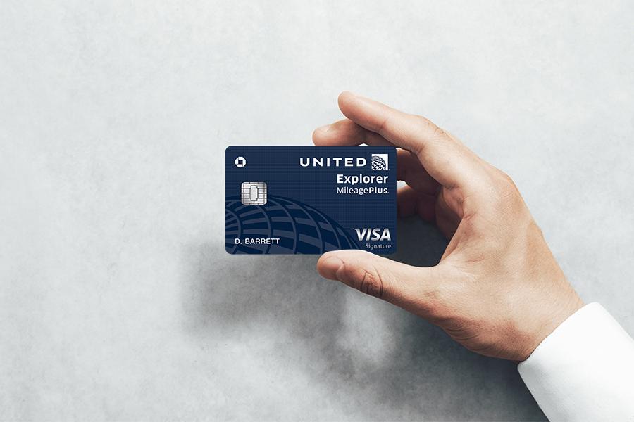 A hand holding a United Explorer Business Card.