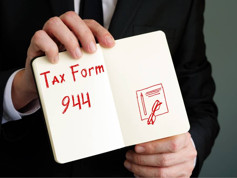Man holding a notebook with tax form 944 written.