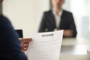 Man holding a resume of the applicant in front of him.