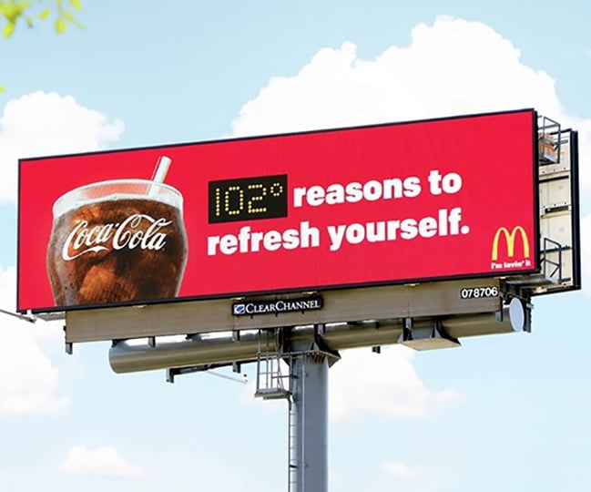 Billboard by Coca-Cola that also shows the current temperature.