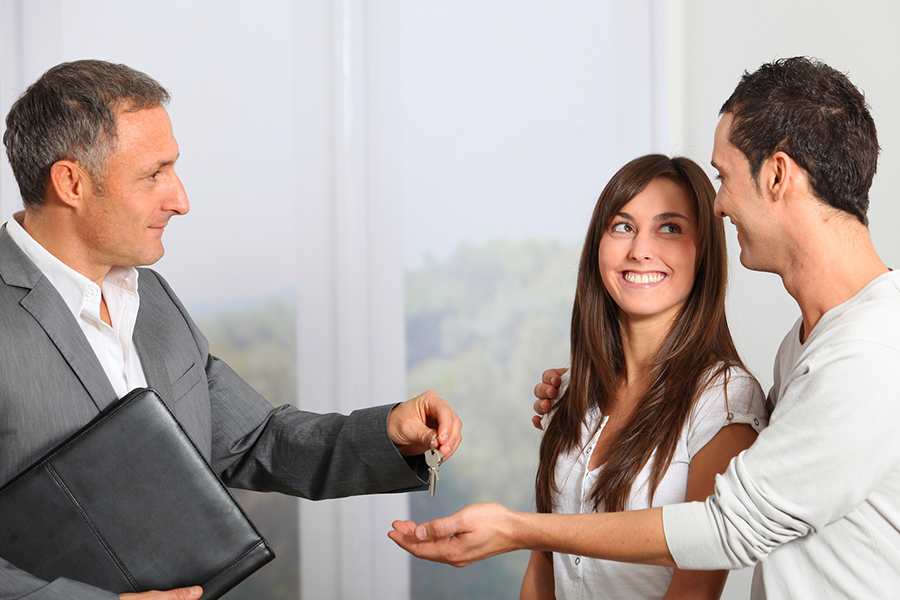 Businessman handing over key to the couple.