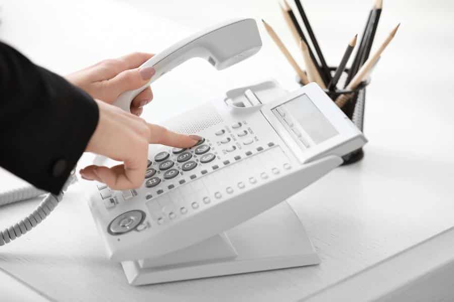Woman using landline phone in office.