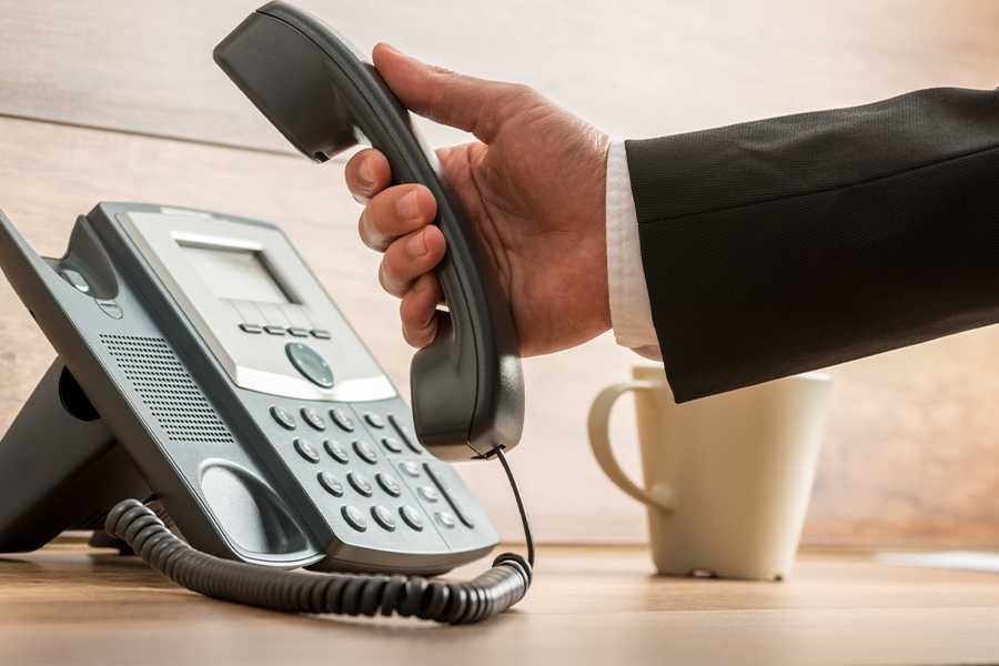 A close up of hand holding a Voip phone.