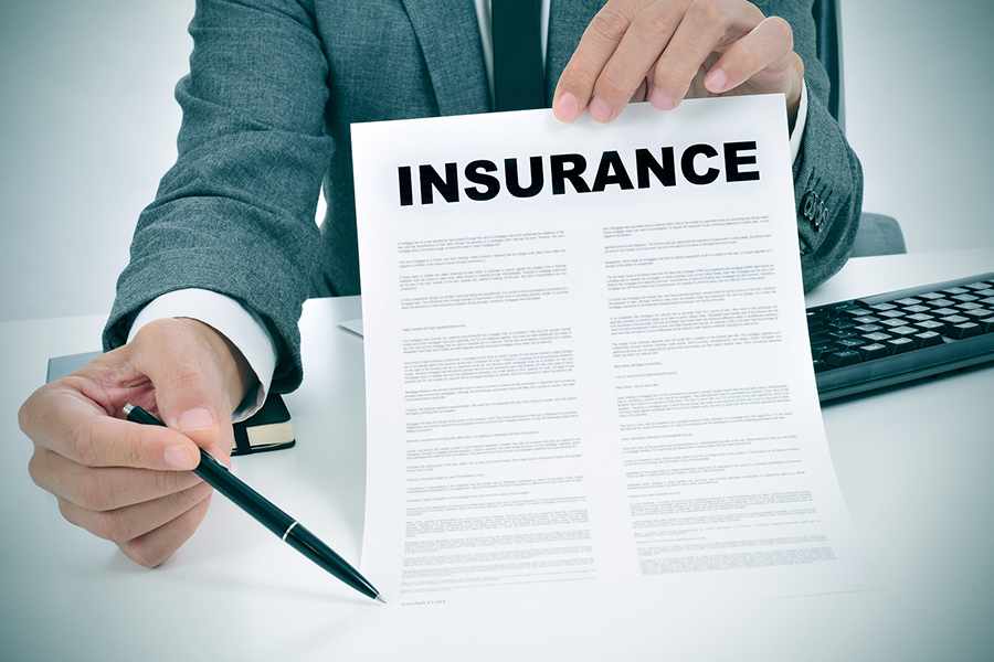 Businessman holding a paper with Insurance written on it and a pen.