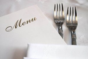 Arranged menu, two forks and a table napkin.
