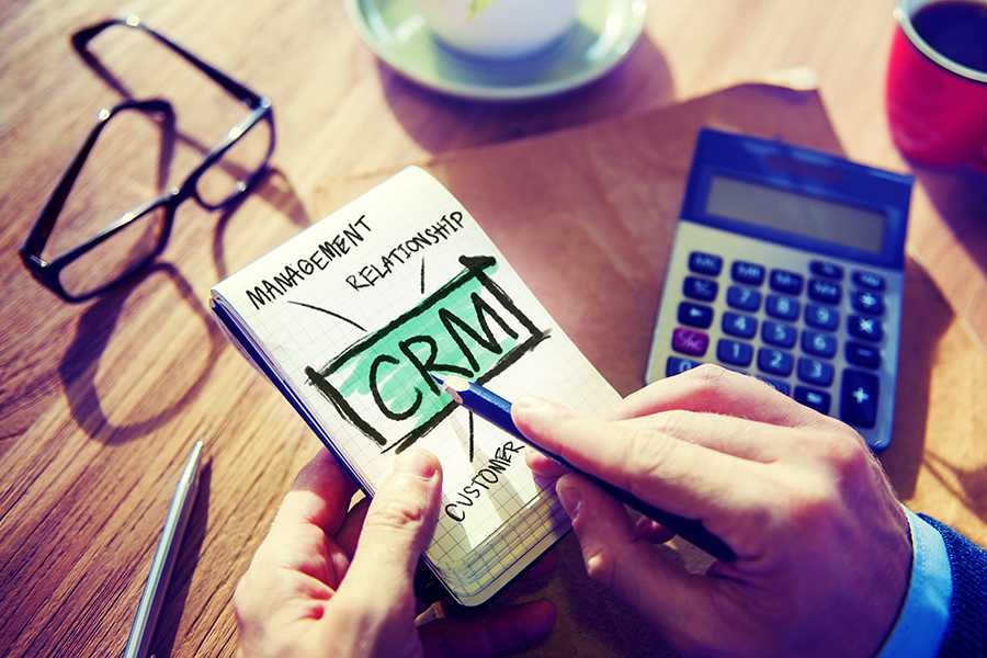 Man's hand is making a CRM concept in a note.
