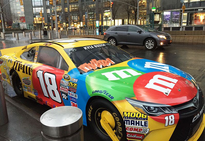 A can from NASCAR parked on a busy New York City street.