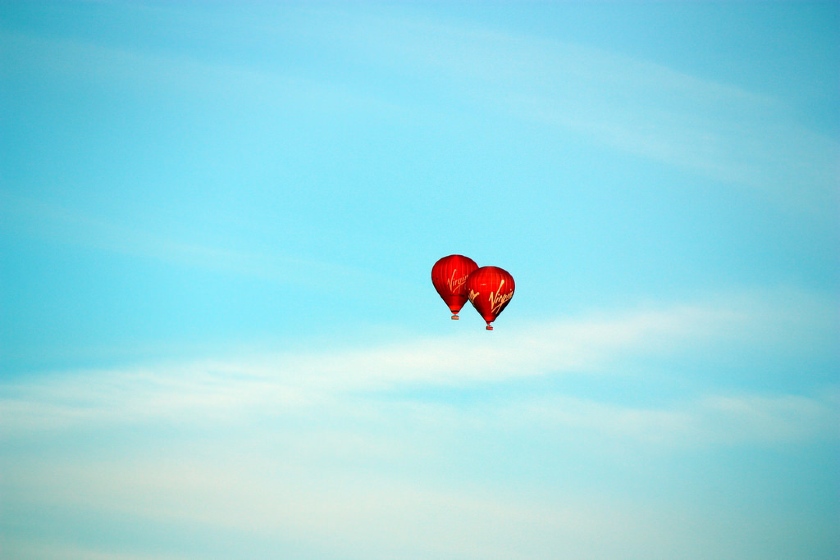 Two hot air balloons branded with the Virgin Airlines logo against a blue sky.