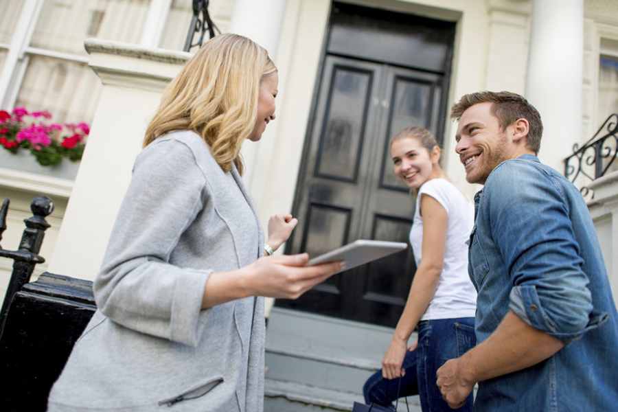 Female Real Estate Agent Showing New House To Couple