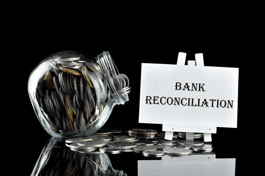 Money in glass containe and white board written Bank Reconciliation