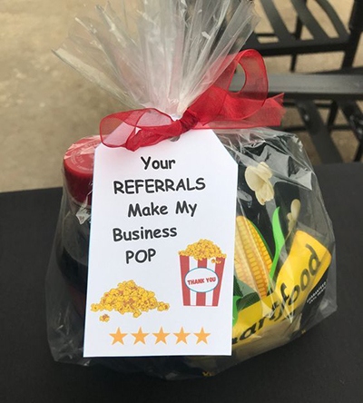Bag of popcorn wrapped with gift tag that says "Your referrals make my business pop."