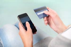 A hand holding a credit card and phone.
