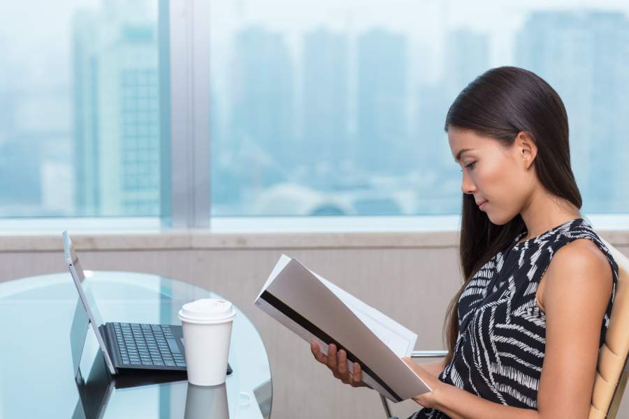 businesswoman reading documents studying paperwork at desk