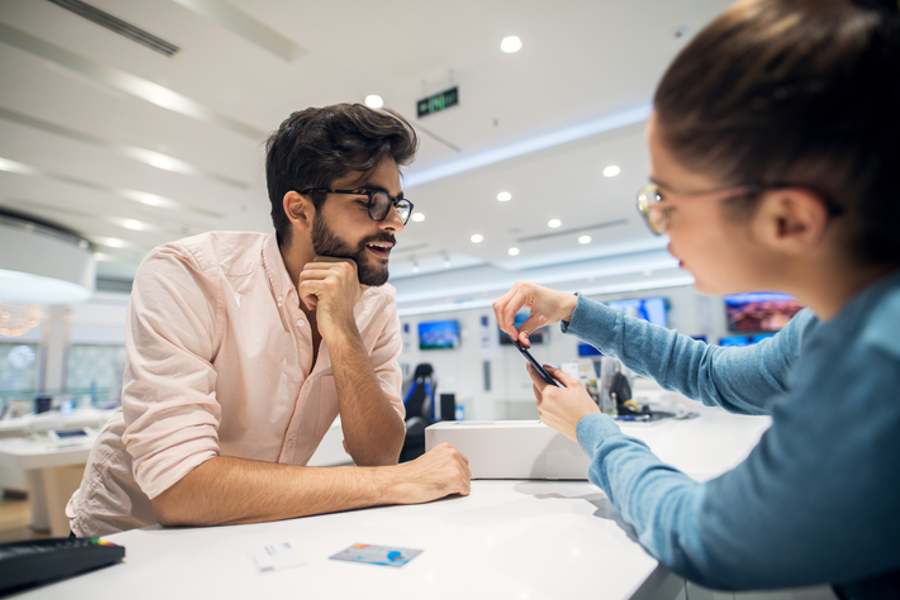 Man getting instructions for a mobile from professional girl seller in a tech store.