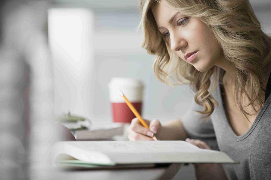 young adult woman studying and taking notes