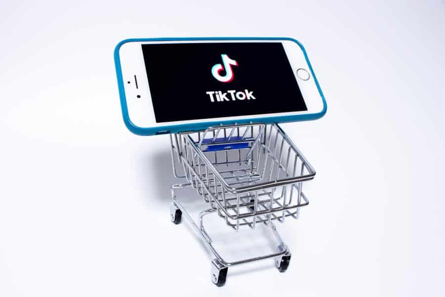 Showing a mini cart with a mobile phone on it, showing a TikTok logo on its screen.