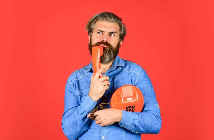 Bearded man holding a retro phone.