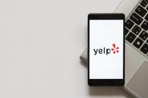 Yelp logo on white screen of mobile phone.
