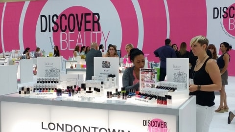 Young business people at COSMOPROF exhibition choosing beauty products.