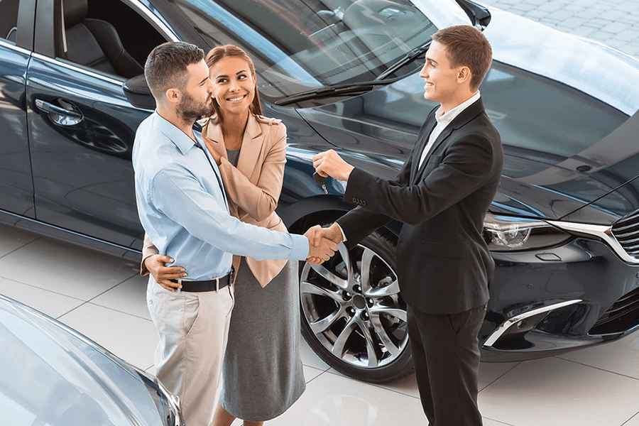 A happy couple receiving their new car keys from the dealer.