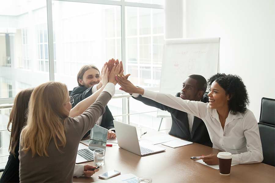 Business team giving high five at office meeting motivated by victory, achievement or good work result.
