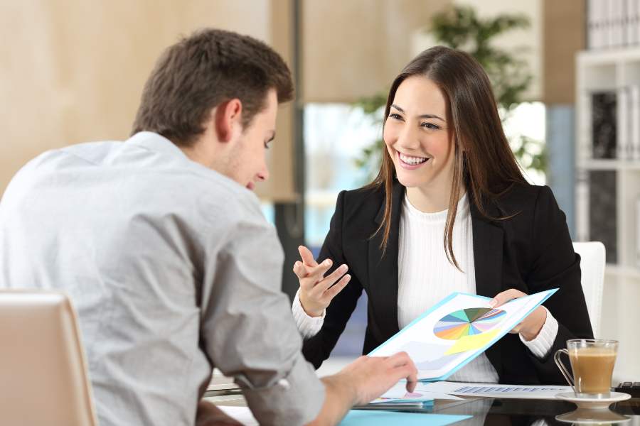 Businesspeople smiling co-working commenting and showing growth graphic and taking a business conversation in an office interior.