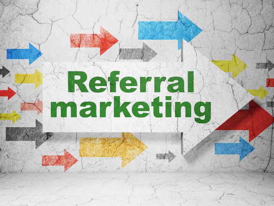 "Referral Marketing" on a white arrow and a concrete wall background printed with arrows in different colors.