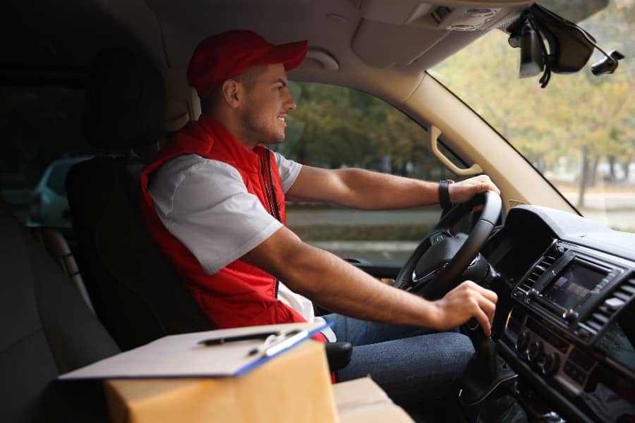 Courier in uniform on driver's seat of car