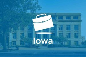 A suitcase with "IOWA" text below it and a building on the background.