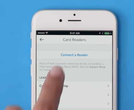 A hand tapping the "Connect a Reader" in the phone screen.