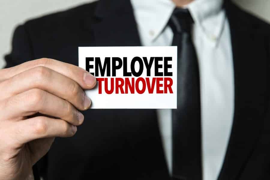 Employee Turnover written on a white card held by a man in suit.