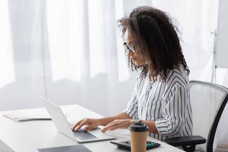 Employee in glasses using laptop and working at home.