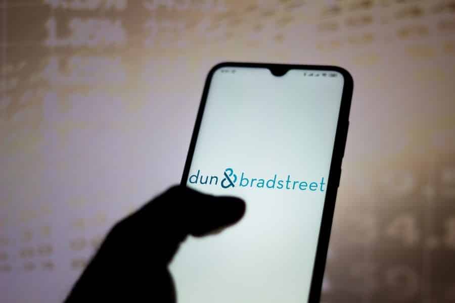 Silhouette hand holding a phone with Dun & Bradstreet logo on the screen.