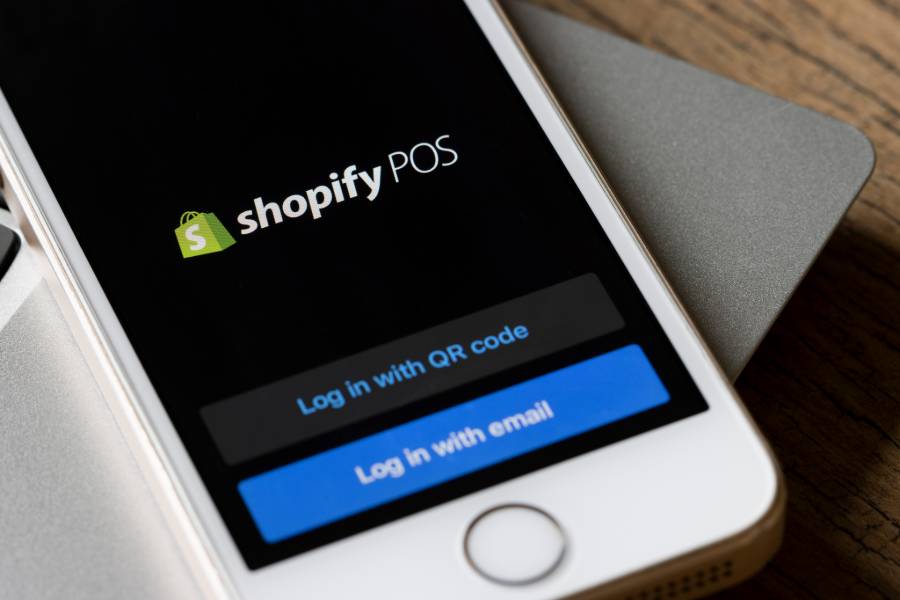 A smartphone with Shopify POS app on screen.