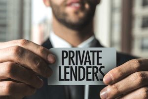 Man in business suit holding a piece of paper with "Private Lender" written on it.